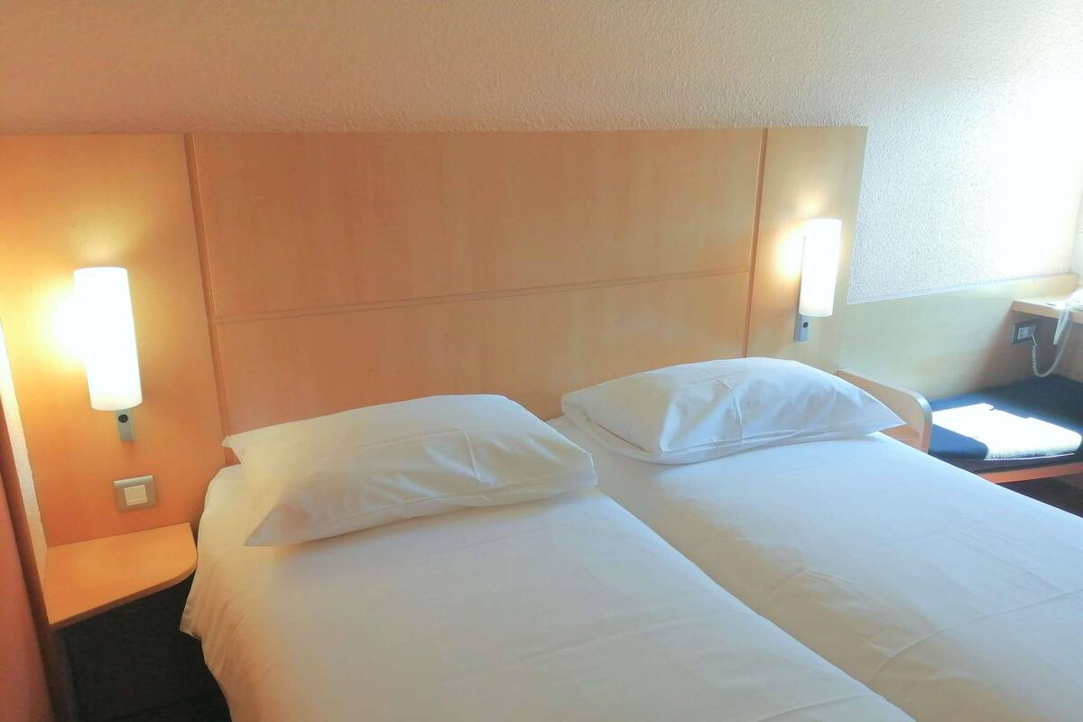 Une chambre d’hôtel avec deux lits, une table de chevet, une lampe et un téléphone.