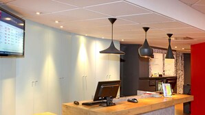 En receptionsdisk med en dator, en mus och en surfplatta. I bakgrunden finns skåp och en röd vägg.
