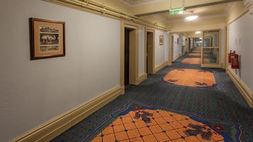 Un pasillo con alfombra estampada, cuadros enmarcados y puertas que dan a otras áreas.