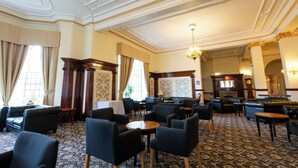 A spacious lobby with multiple seating areas, a grand fireplace, and elegant architectural details.