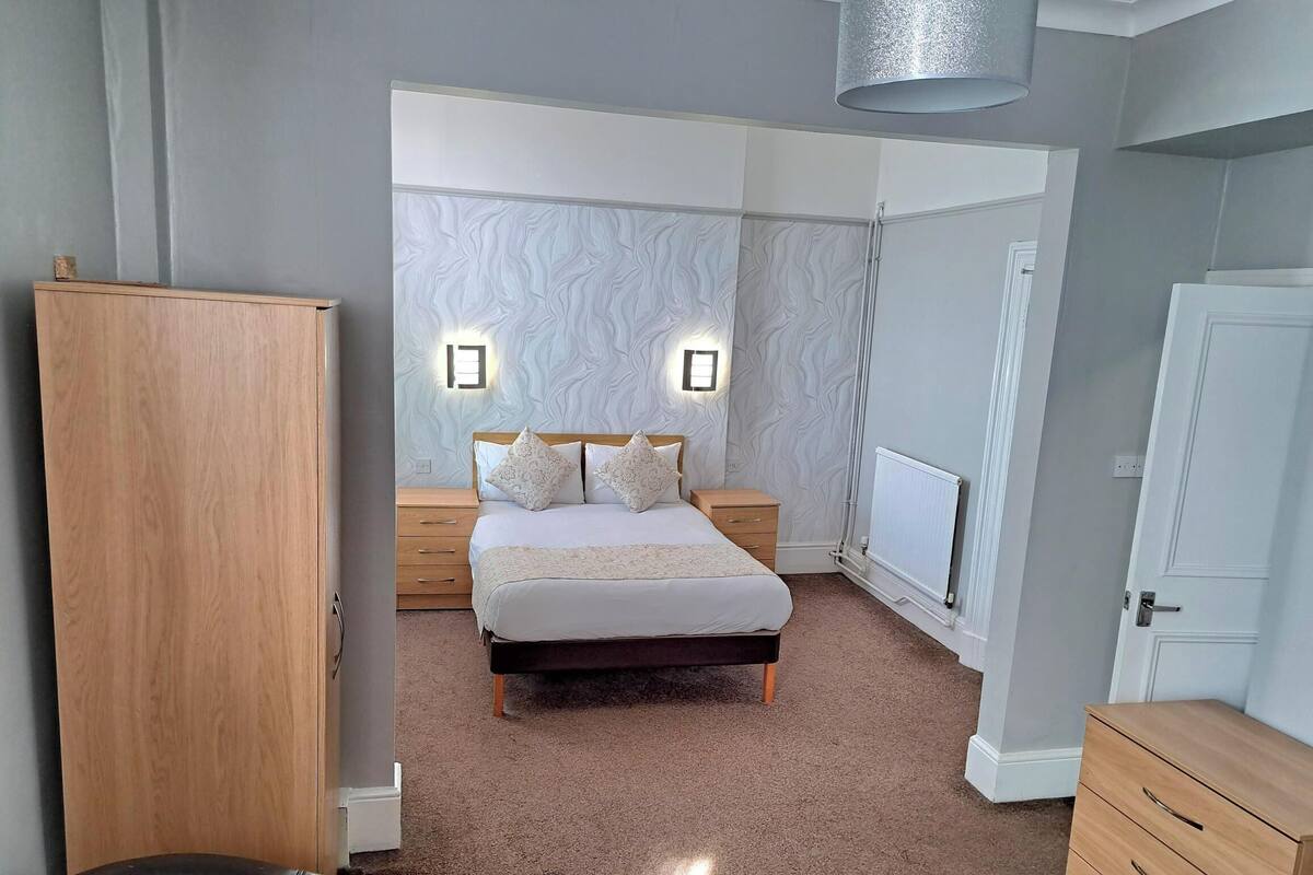 A bedroom with a bed, bedside tables, a wardrobe, and a radiator.