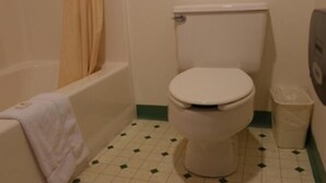 A small bathroom with a toilet, a bathtub, and a trash bin. - State Line Inn (Hagerstown)