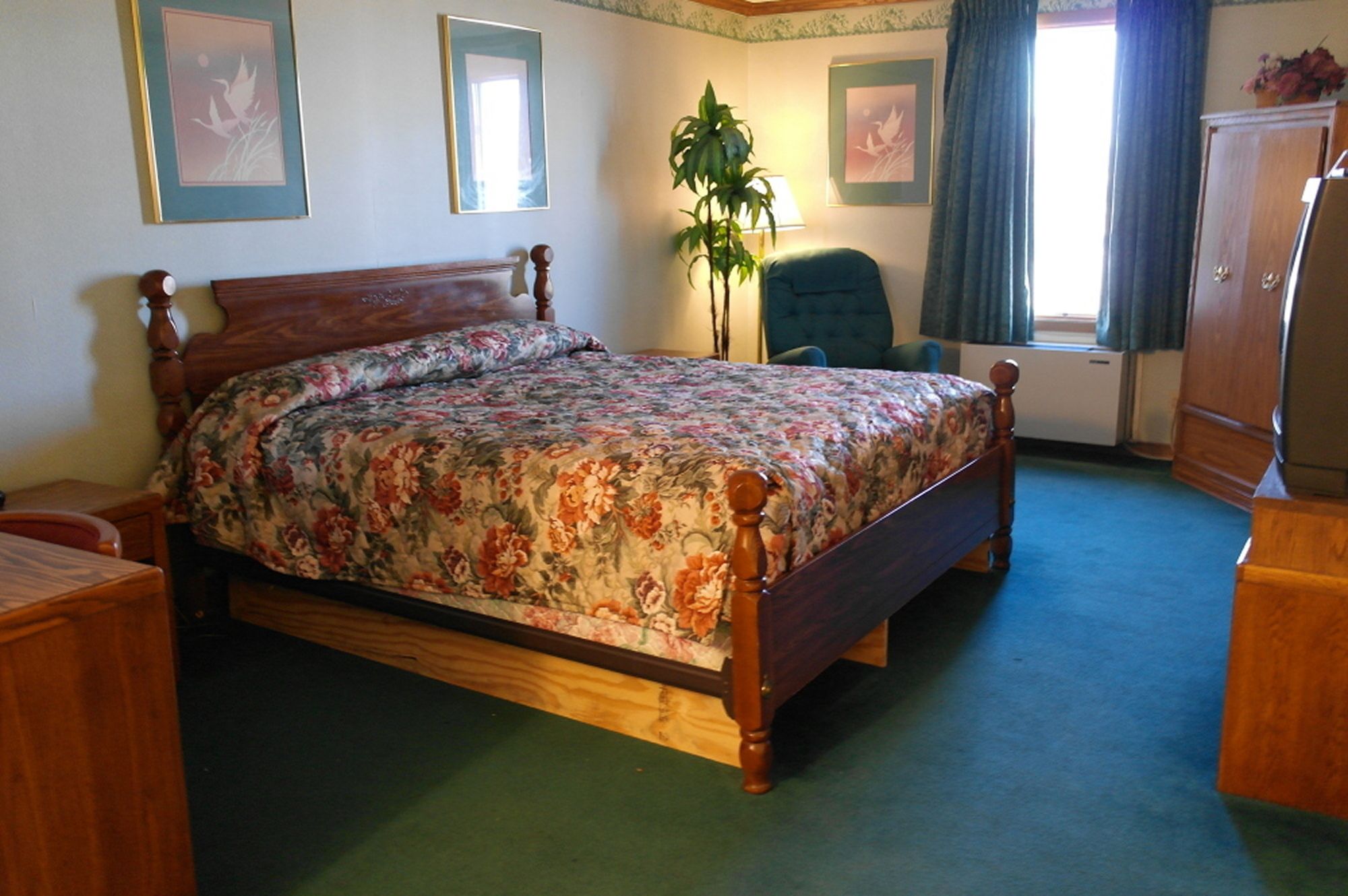 Een slaapkamer met een houten bed, een stoel, een bureau en een dressoir.