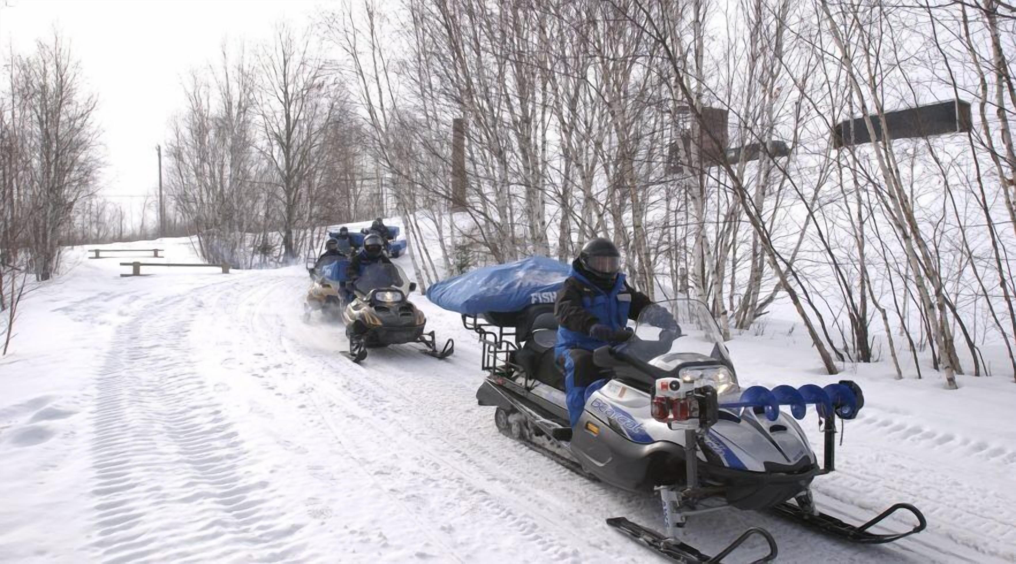 A snowmobile trail with riders in winter gear.