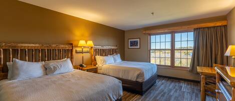 A hotel room with two beds, a wooden dresser, a window with a view, and a framed picture on the wall.
