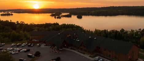 Un chalet doté d’un grand parking et offrant une vue sur un lac au coucher du soleil.