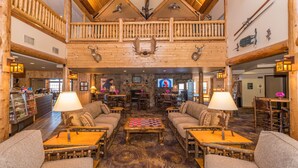 A spacious lobby with high ceilings, wooden beams, and a checkered coffee table. - Grand Ely Lodge Resort & Conference Center (Ely)