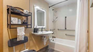 Une salle de bain équipée d’une douche, d’un lavabo, d’un miroir et d’une étagère où sont rangés les articles de toilette.