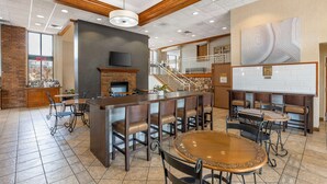 A spacious bar area with a fireplace, multiple seating options including bar stools and tables, and a staircase leading to an upper level. - Best Western Plus Landing View Inn & Suites (Branson)