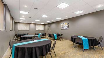 A conference room with multiple tables, chairs, and a carpeted floor.