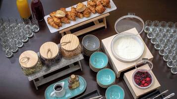 A breakfast buffet with croissants, fruit, and beverages.