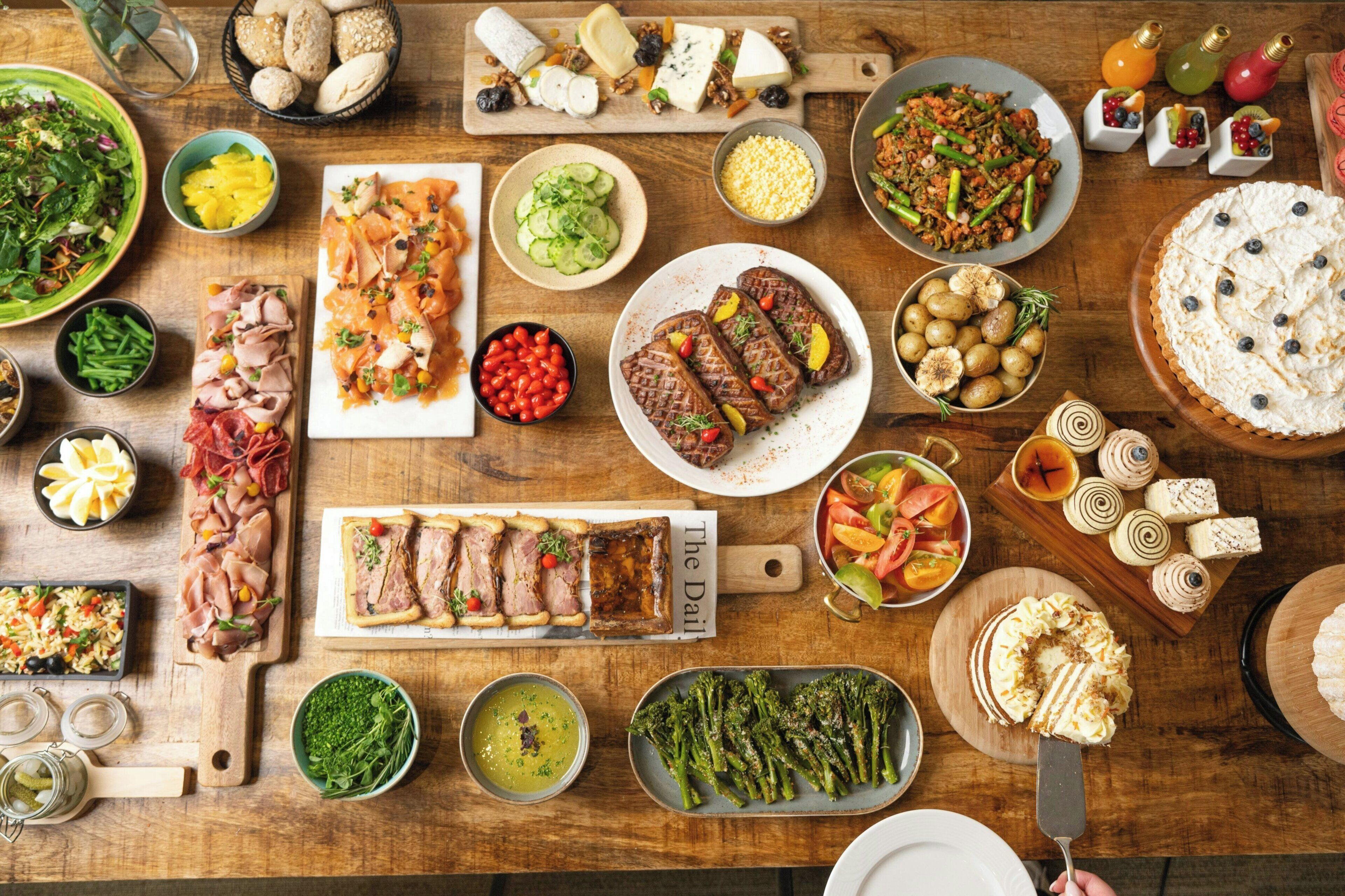 A variety of food items and dishes arranged on a wooden table.
