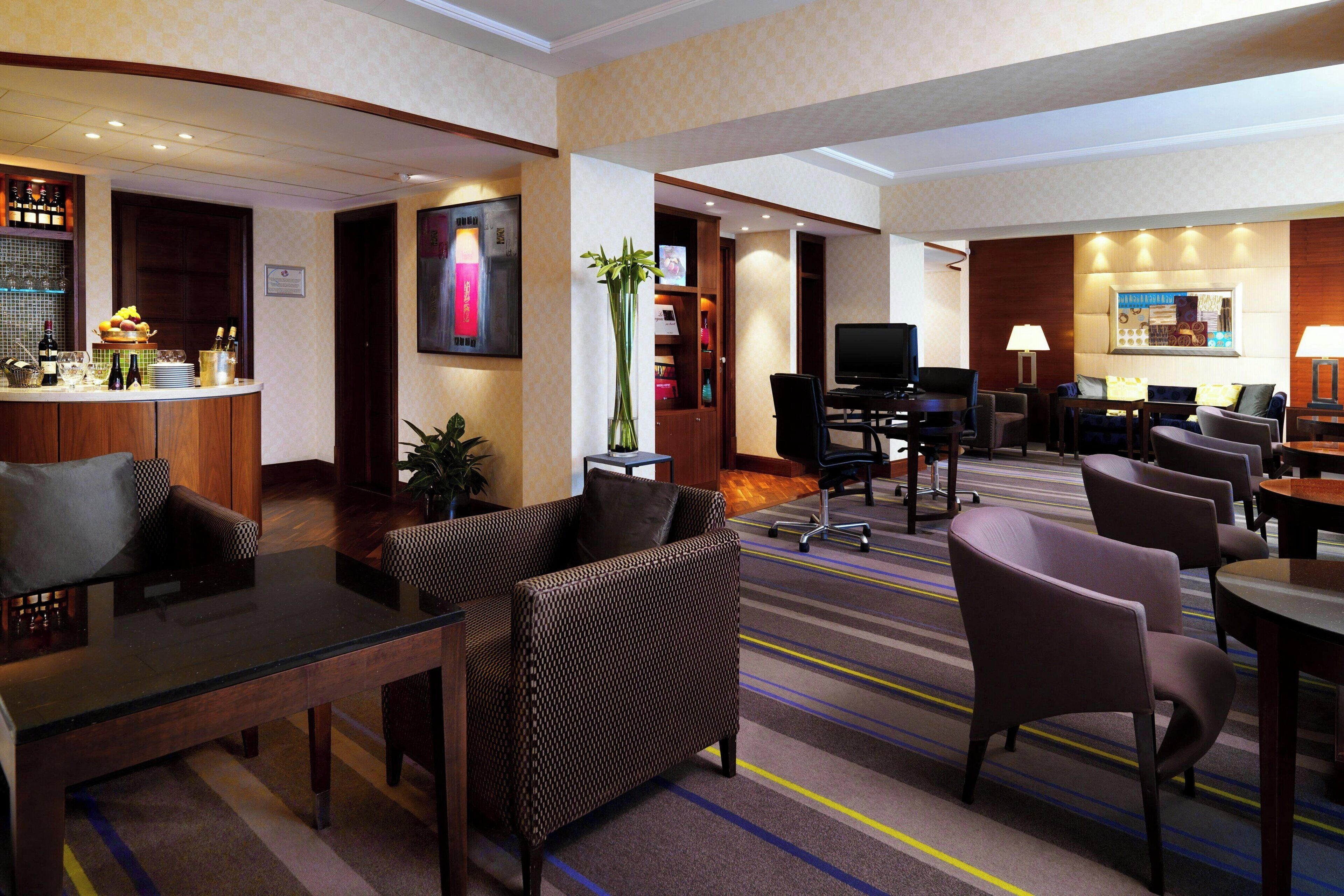 Een hotel lobby met een receptiebalie, een zithoek en een televisie.