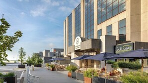 A hotel exterior with outdoor seating, a Sheraton sign, and a Gullivers restaurant sign. - Sheraton Brussels Airport Hotel (Zaventem)