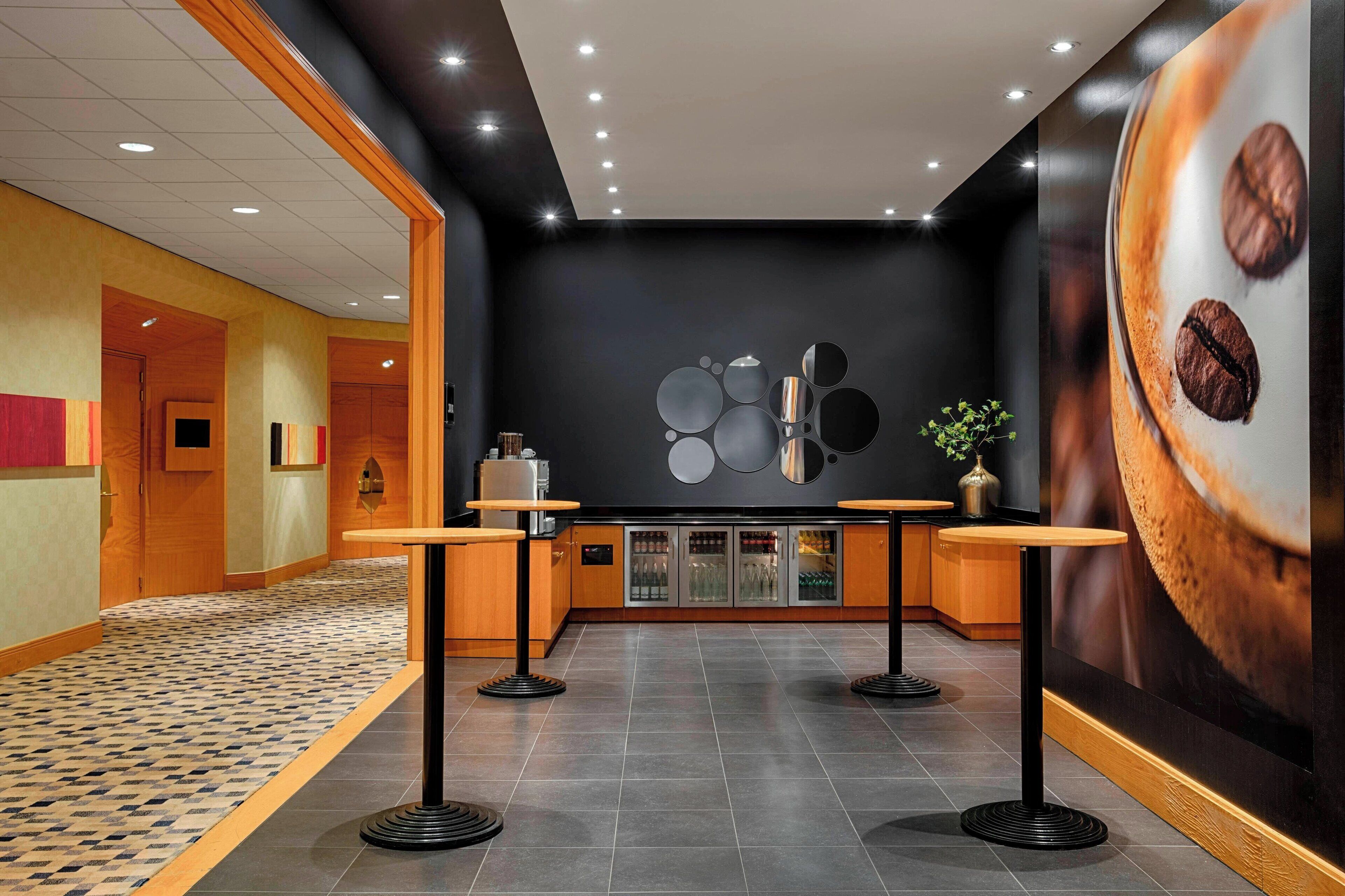 A modern lobby with a checkered floor, wooden accents, and a wall with a coffee-themed mural.