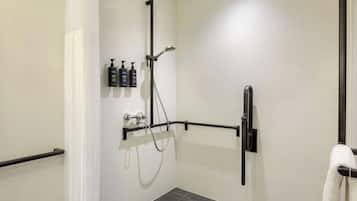 Un baño moderno con ducha, un perchero y artículos de aseo en un estante de pared.