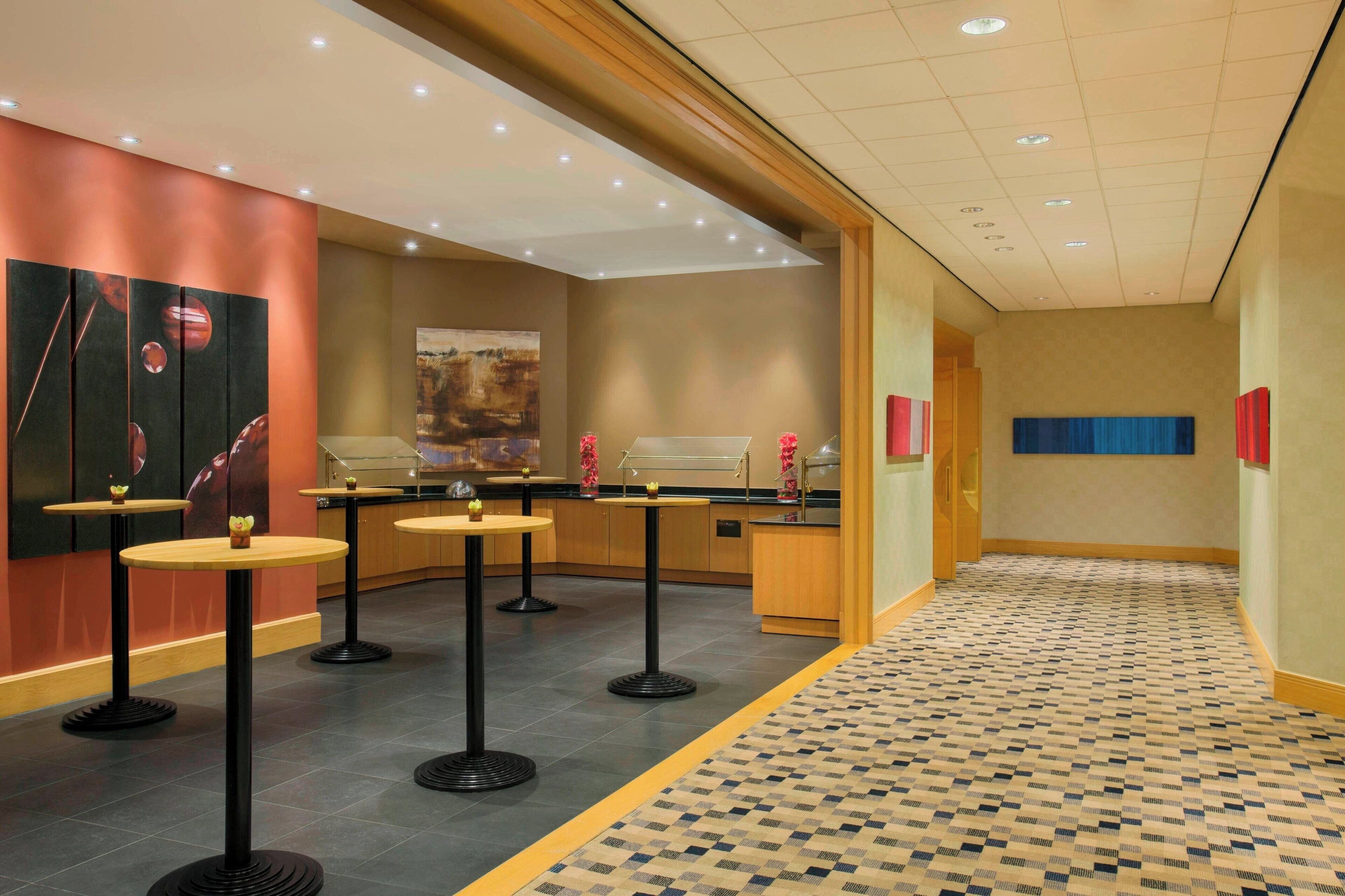 A hotel lobby with a check-in counter, multiple round tables, and a patterned floor.