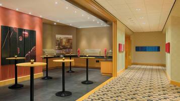 A hotel lobby with a check-in counter, multiple round tables, and a patterned floor.