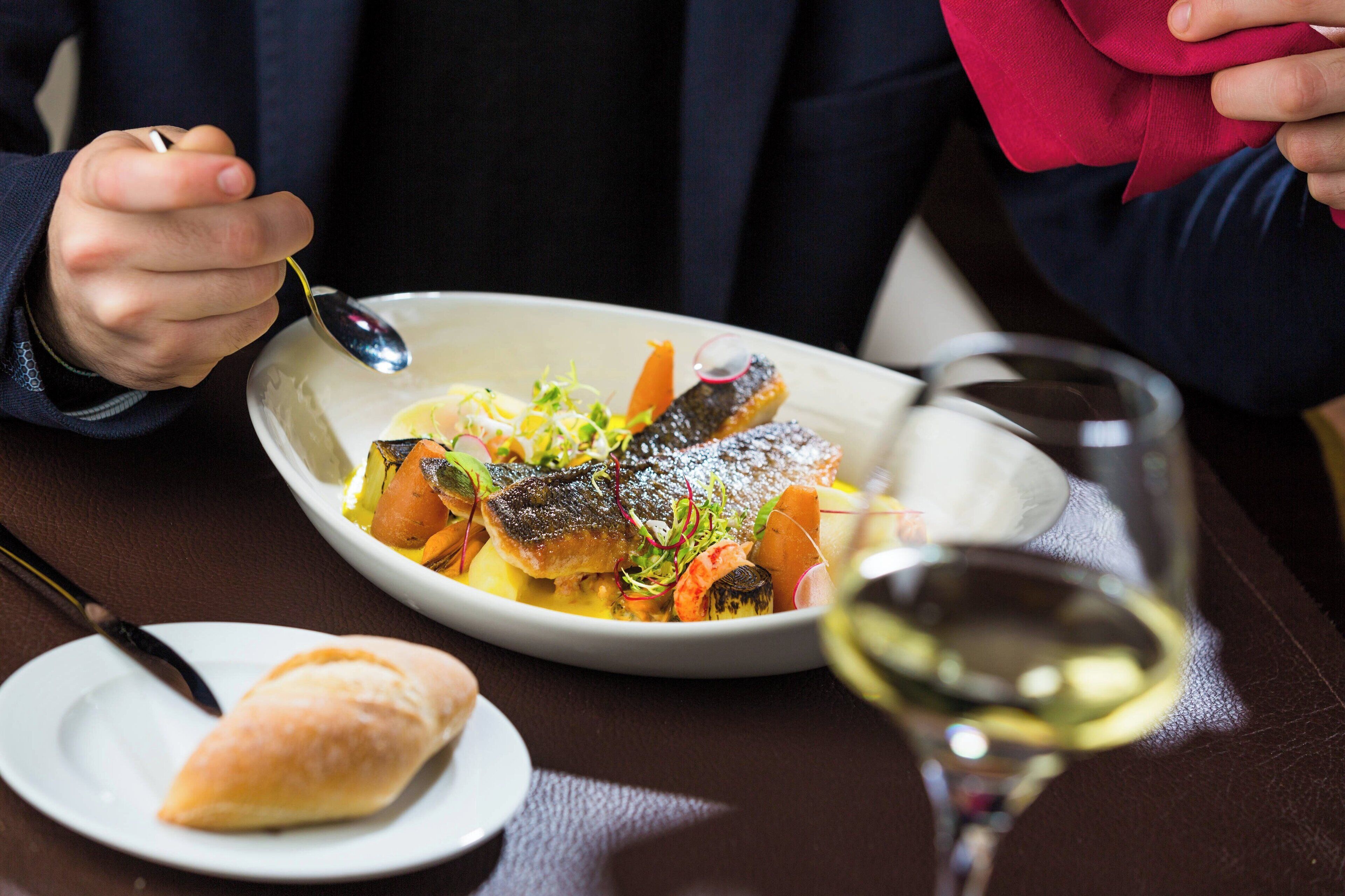 A dining table with a plate of food, a glass of wine, and a napkin.