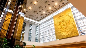 A modern interior with a high ceiling, large windows, and a central sculpture. - Sheraton Brussels Airport Hotel (Zaventem)