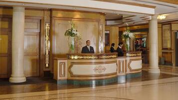 A reception area with a marble floor, a reception desk, and two large vases with flowers.