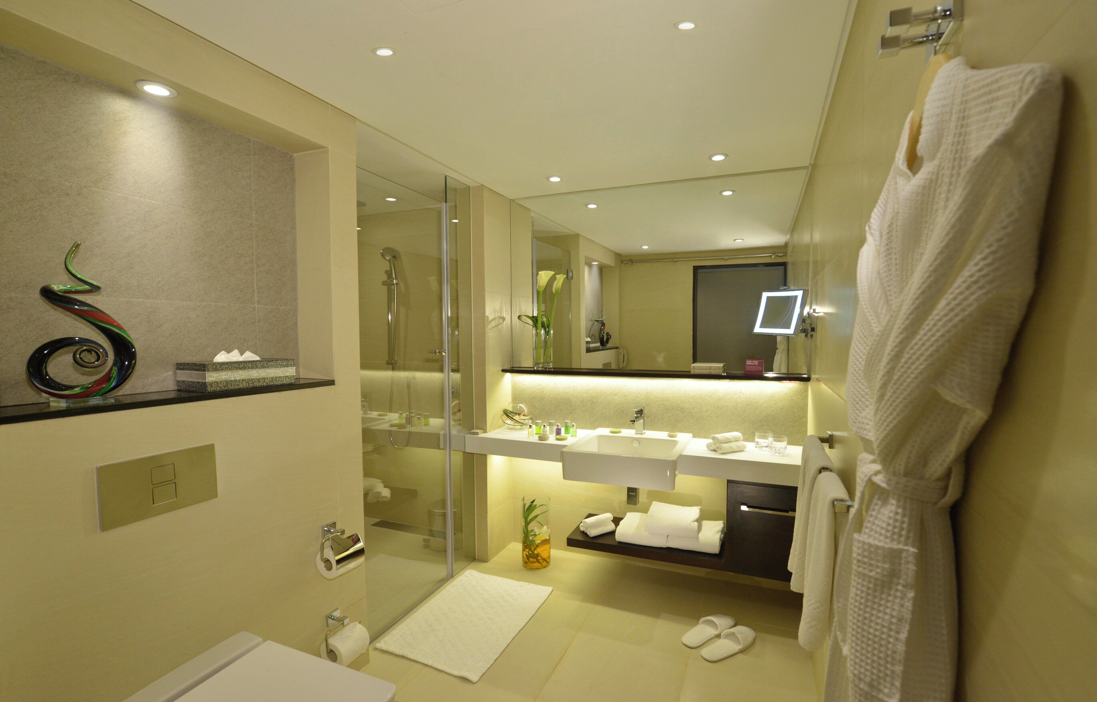 A modern bathroom with a glass shower enclosure, a white sink, and a mirror above the vanity.