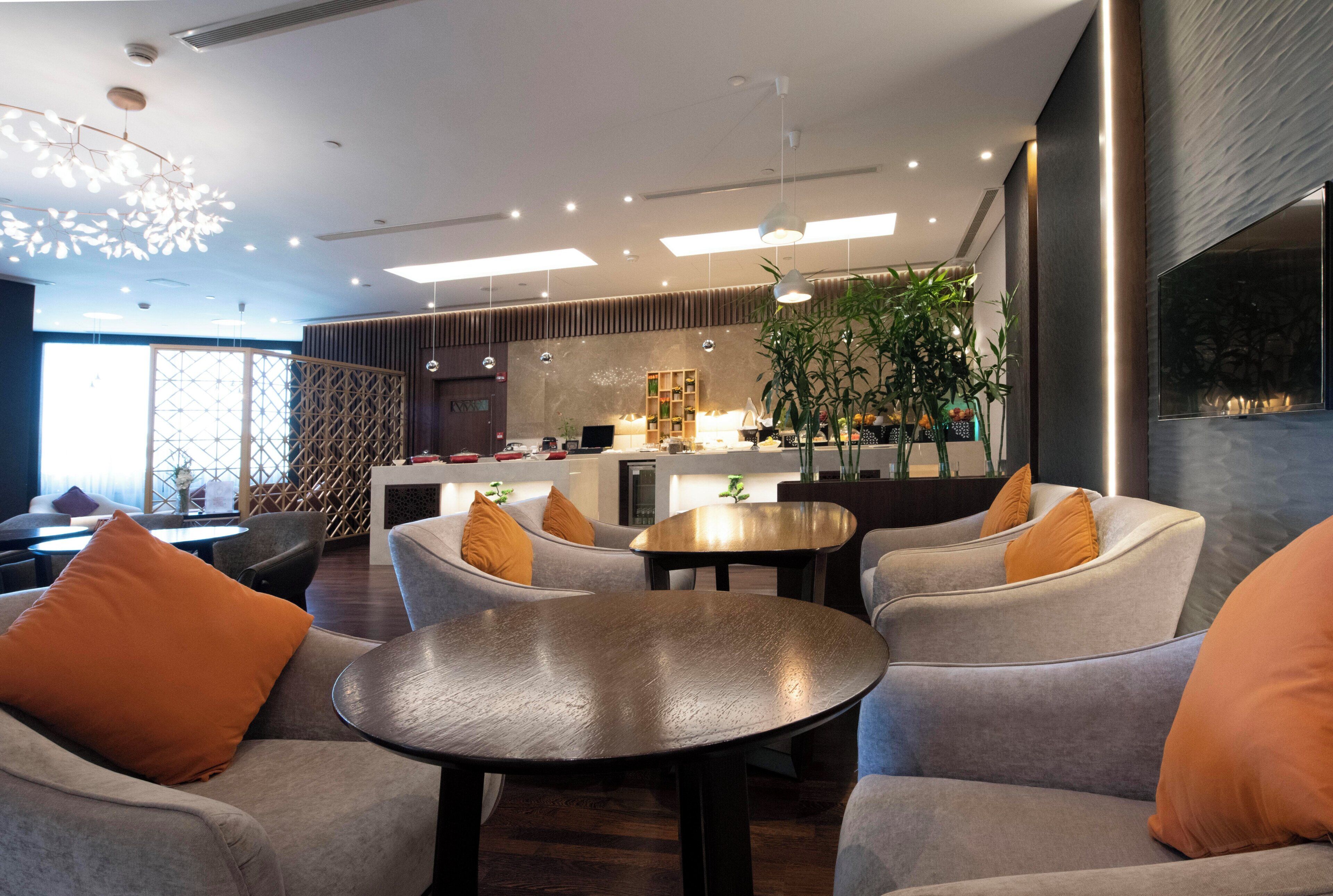 Un interior moderno con sofás, una mesa redonda y una zona de cocina con una planta.