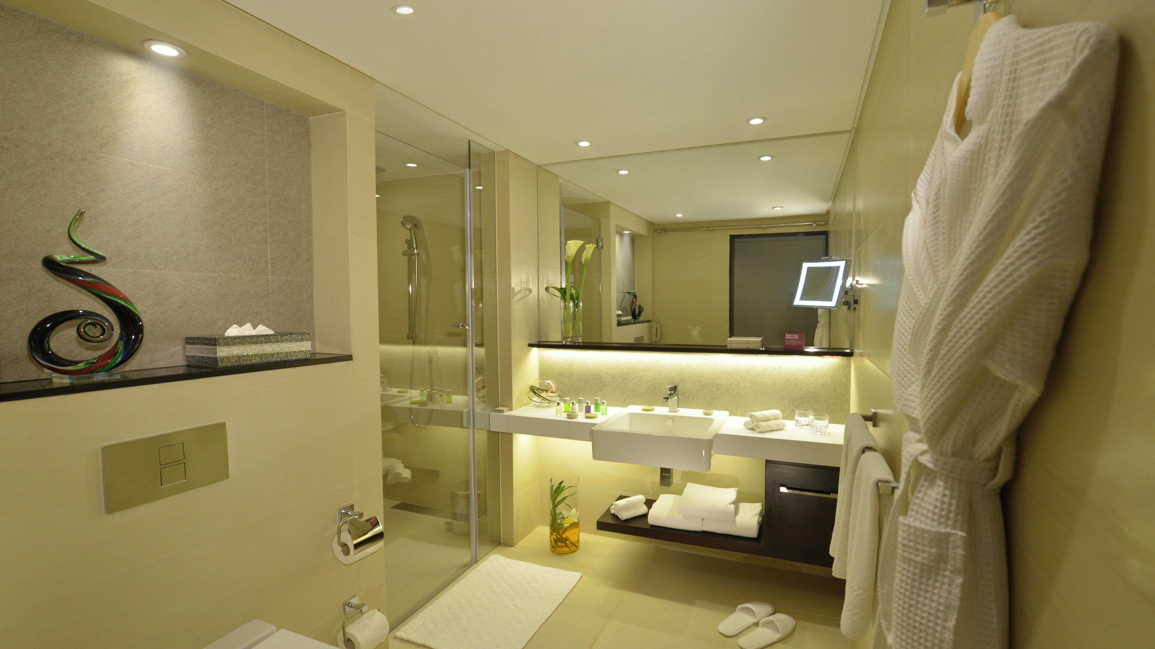 A modern bathroom with a glass-enclosed shower, a vanity with a mirror, and a towel rack.