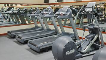 A row of treadmills in a gym with mirrors on the wall.