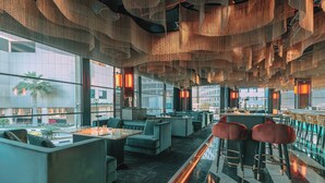 Ein modernes Interieur mit Sitzbereichen, einer Bar und großen Fenstern mit Blick hinaus.