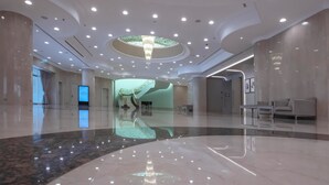 Eine großzügige Lobby mit Marmorboden, einem zentralen Kronleuchter und einer Wendeltreppe.