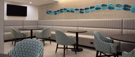 A modern lounge area with a sofa, chairs, and tables.