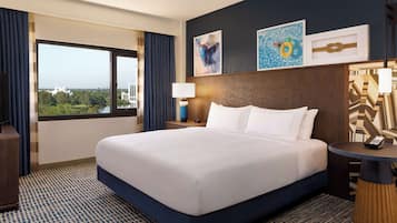 Ein Hotelzimmer mit einem großen Bett, Blick auf die Stadt und Kunstwerken an der Wand.