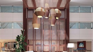 A spacious lobby with a high ceiling, wooden beams, and a central seating area with a round rug.