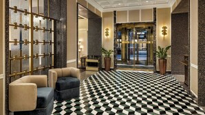 A lobby with a checkered floor, seating area, and a glass entrance.