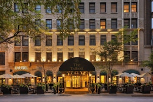 A hotel entrance with a marquee sign, outdoor seating, and a well-lit facade.