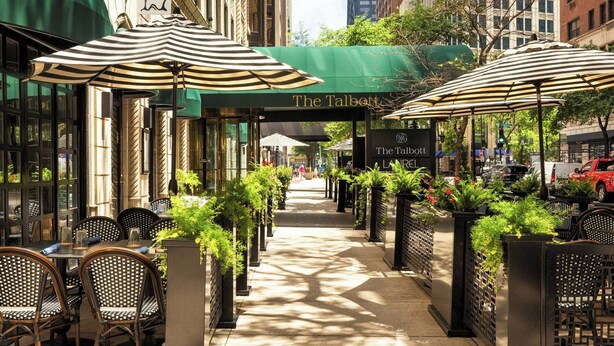 A street view with outdoor seating, a green awning, and a sign for 'The Talbott'.