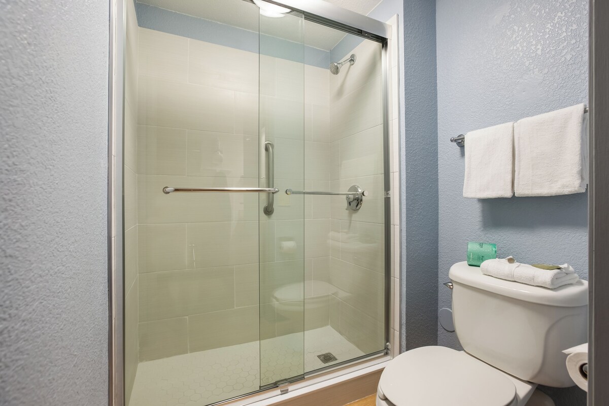 A bathroom with a glass-enclosed shower, a toilet, and a towel rack.
