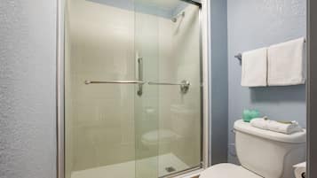 Un baño moderno con ducha de vidrio, inodoro blanco y barra para toallas.