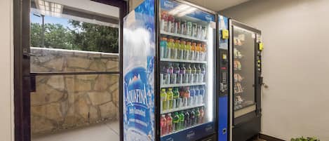 A vending machine stocked with various beverages, including water and soda, in a commercial setting.