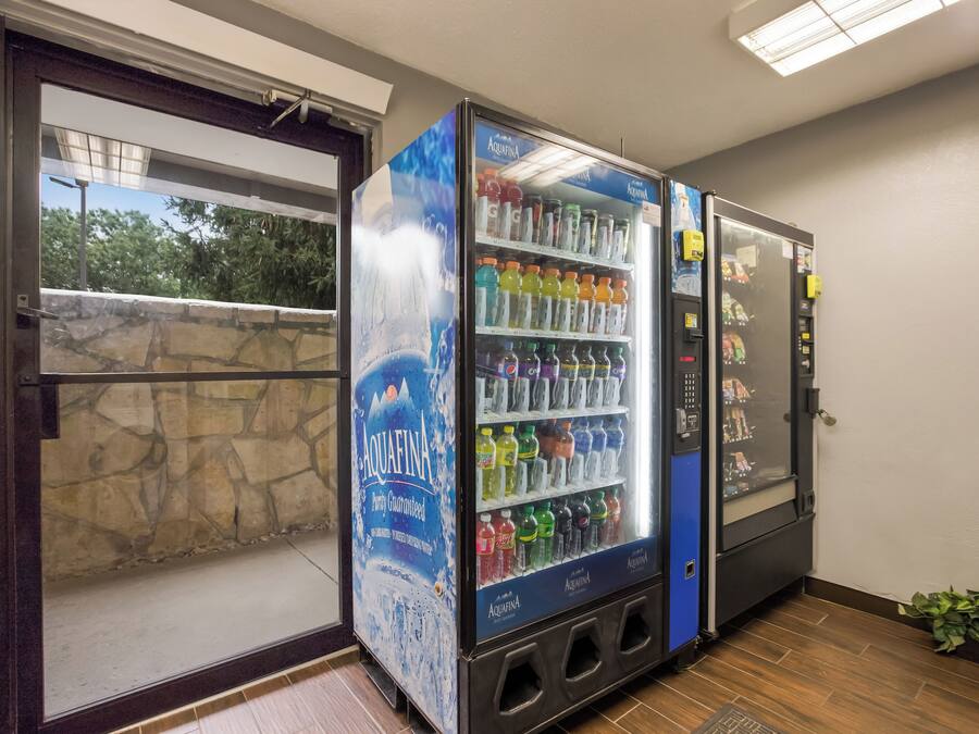 Máquina expendedora llena de diversas bebidas, como agua y refrescos, en un entorno comercial.