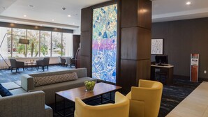 Un vestíbulo moderno con zona de estar, una gran obra de arte abstracta y un mostrador de recepción.