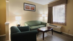 A living room with a green sofa, a small table, two lamps, and a window with curtains.