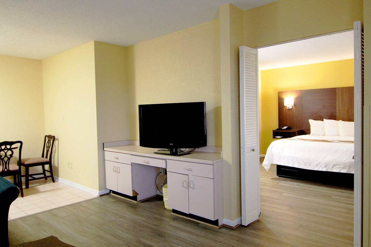 A hotel room with a bed, a television on a desk, and a chair.