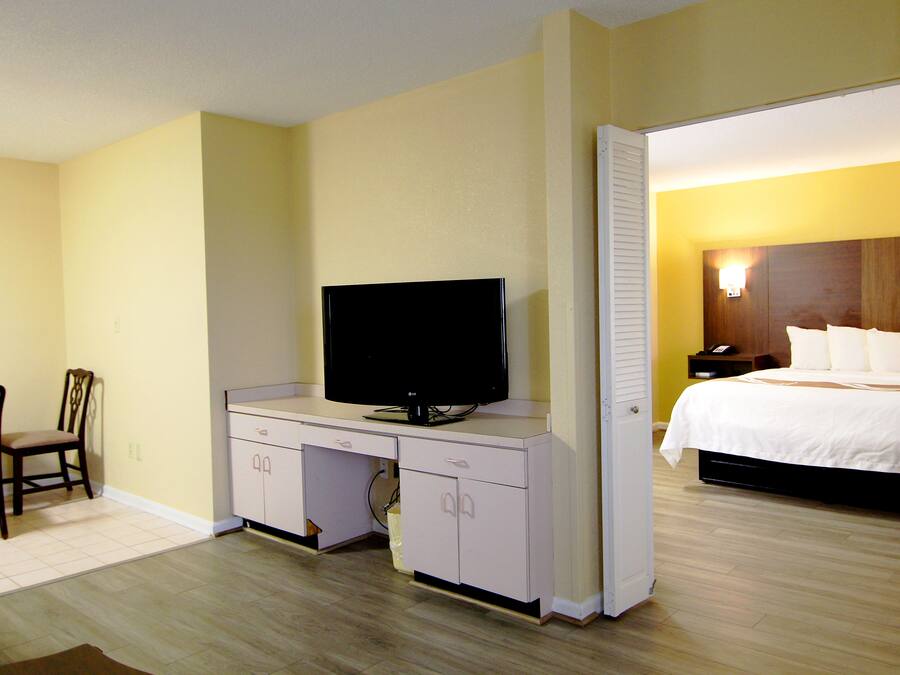 Una habitación de hotel con una cama, un televisor en un escritorio y una silla.