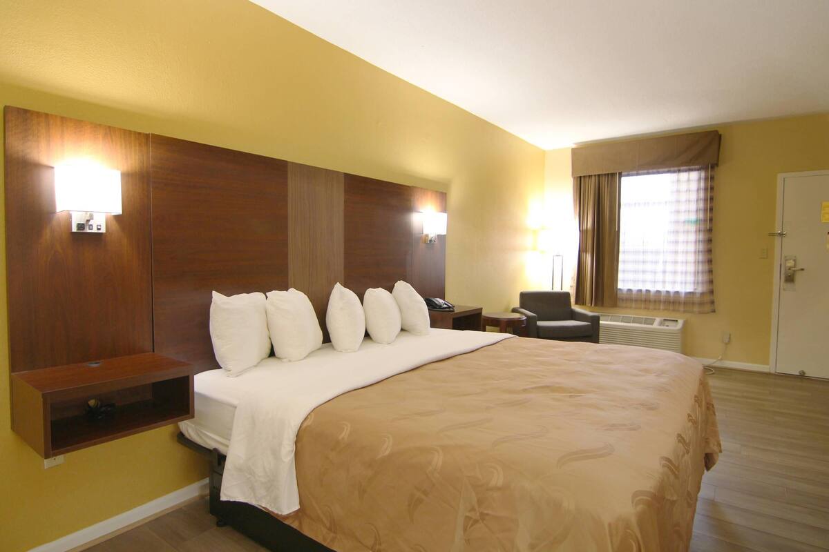 A hotel room with a large bed, bedside tables, a chair, and a desk.