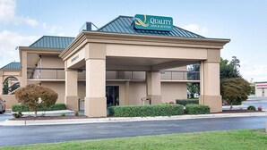 A hotel with a sign reading "Quality Inn & Suites" featuring a covered entrance and a two-story structure.