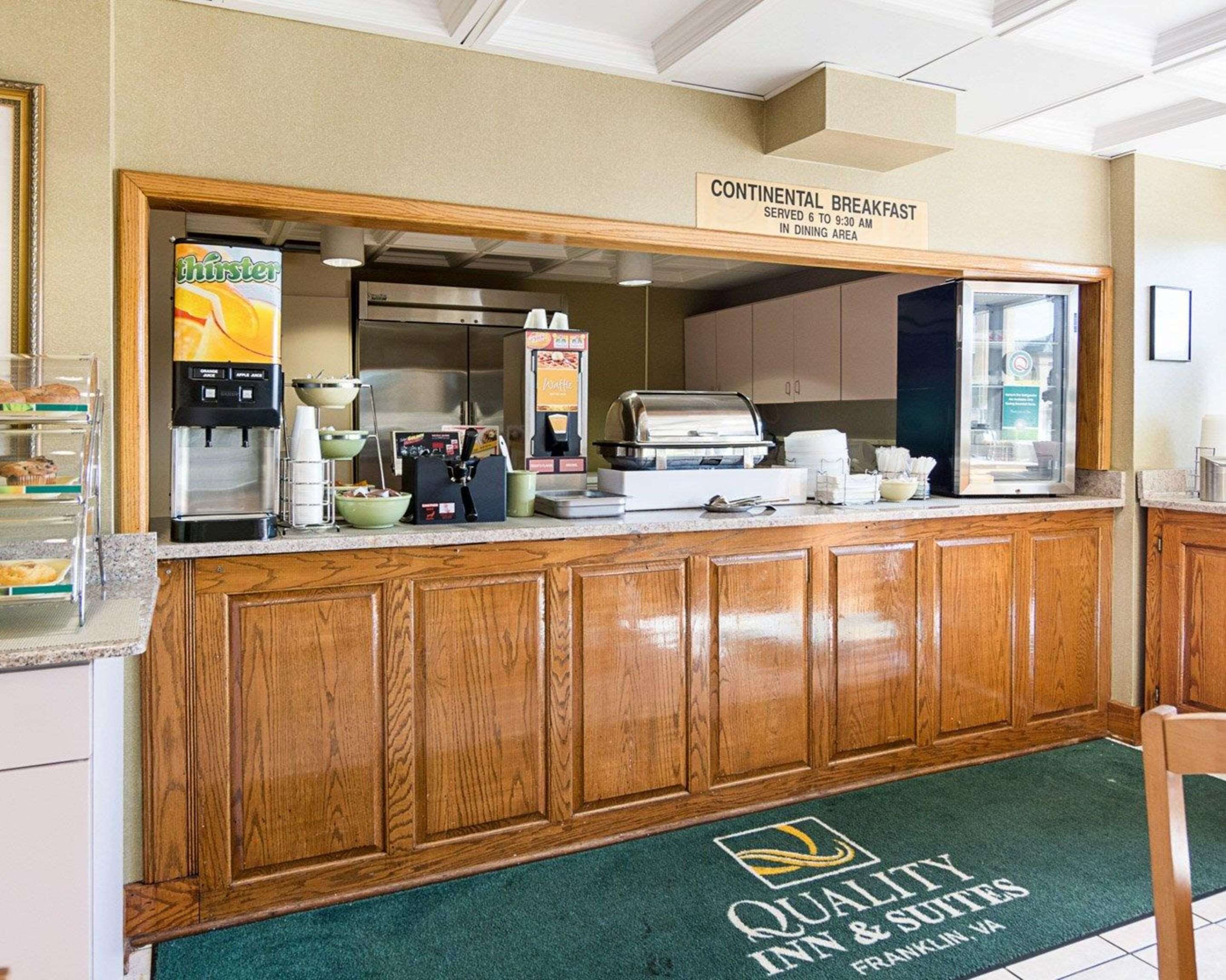 Un espace dédié au petit-déjeuner continental, équipé d’une machine à café, de boîtes de céréales et d’un panneau indiquant les heures de service.