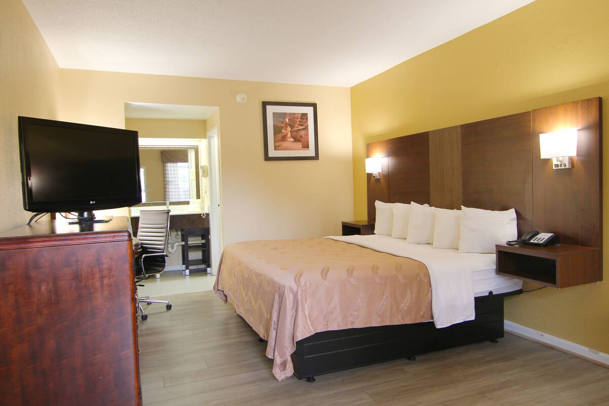 A hotel room with a bed, a television, a desk, and a chair.