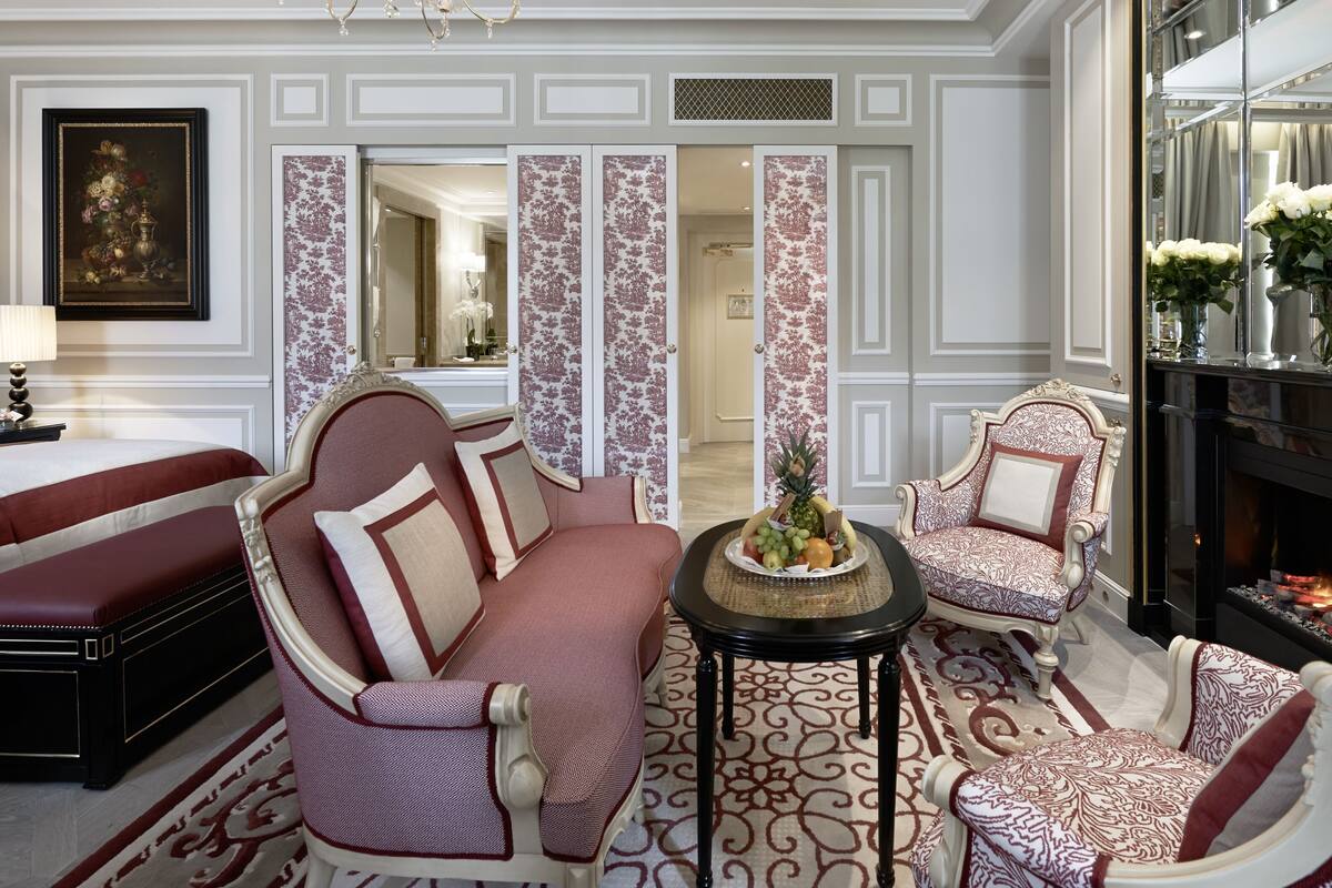 A luxurious living room with a sofa, armchairs, a coffee table, and a fireplace.